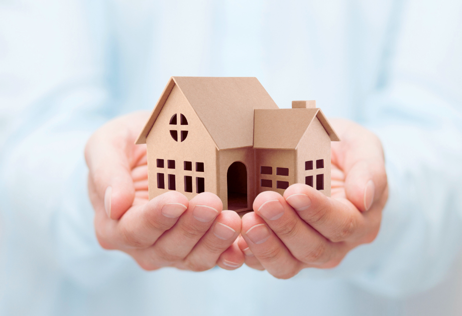 a hand holding a small cardboard house